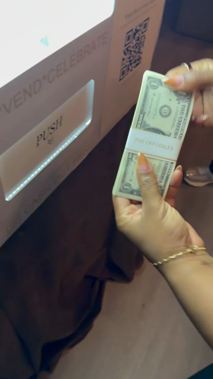 A guest reaching into the station to collect their dollar bundles