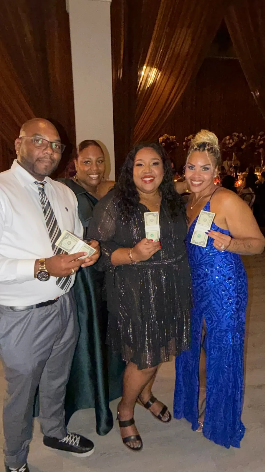 Four guests smiling with their US dollar bundles at a reception