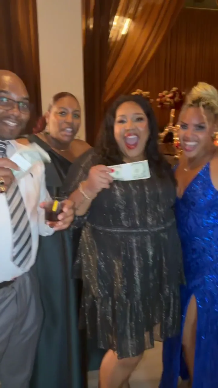 Four guests smiling and holding notes together at a reception